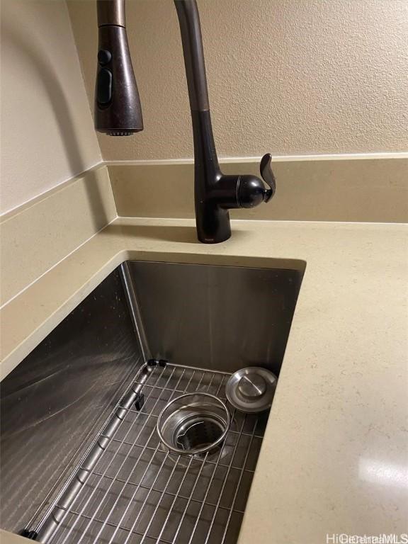 interior details with a textured wall and a sink