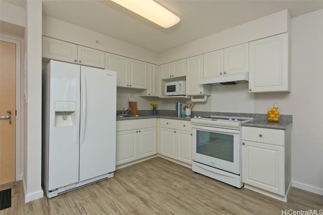 kitchen with dark countertops, white appliances, white cabinets, and under cabinet range hood