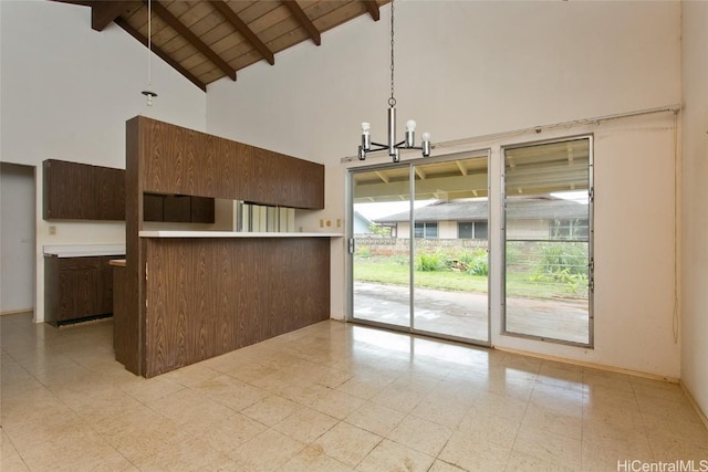 kitchen with high vaulted ceiling, a notable chandelier, wood ceiling, hanging light fixtures, and beam ceiling