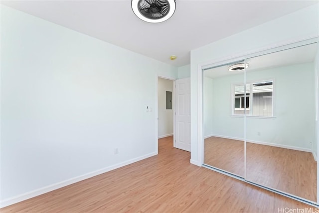 unfurnished bedroom with electric panel, baseboards, visible vents, wood finished floors, and a closet