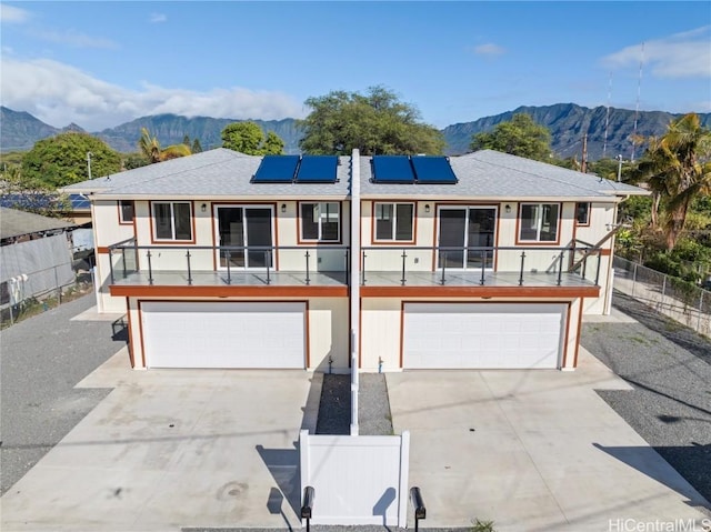 ranch-style house with a garage, roof mounted solar panels, fence, and a mountain view