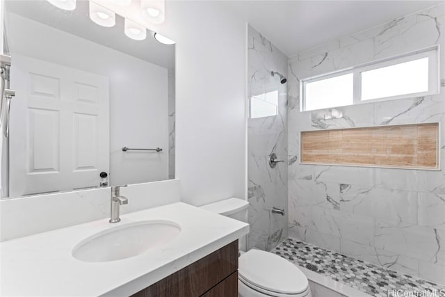 bathroom featuring toilet, a marble finish shower, and vanity