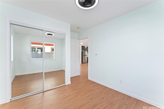 unfurnished bedroom with visible vents, baseboards, a closet, freestanding refrigerator, and light wood finished floors