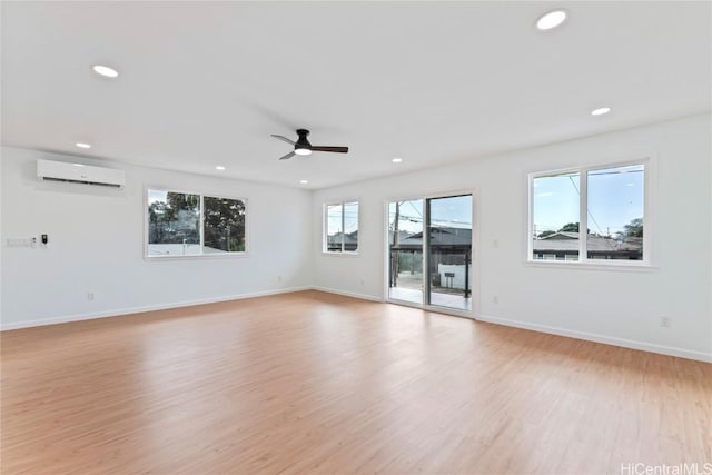 unfurnished room featuring light wood-type flooring, recessed lighting, a wall unit AC, and baseboards