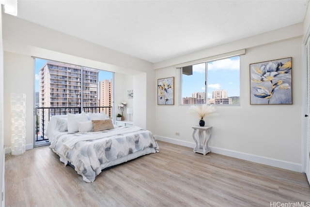 bedroom featuring a view of city, wood finished floors, and baseboards