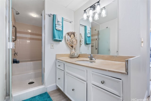 bathroom featuring a shower with door, vanity, and wood finished floors