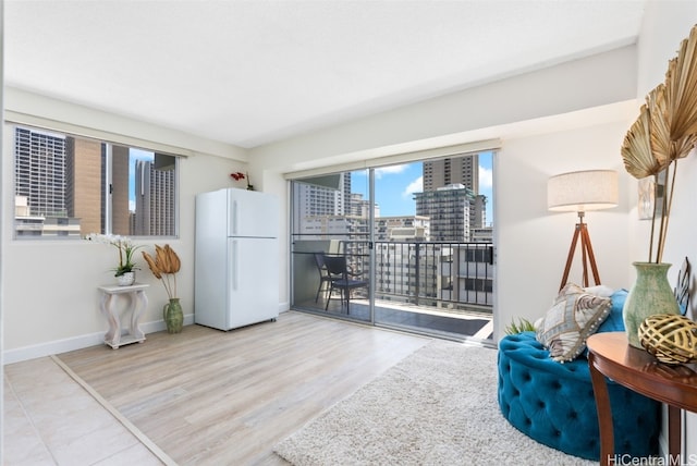 sitting room with a view of city, wood finished floors, and baseboards