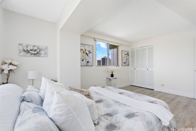 bedroom with a closet, light wood-style flooring, and baseboards