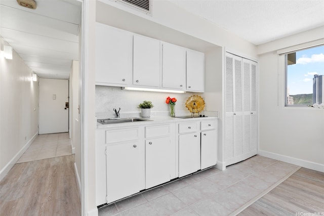 2440 Kuhio Ave Unit 1101, Honolulu, HI 96815 - kitchen featuring light countertops, light wood-style floors, and white cabinetry