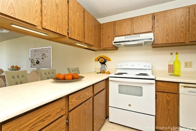 kitchen featuring light countertops, white appliances, brown cabinetry, and under cabinet range hood