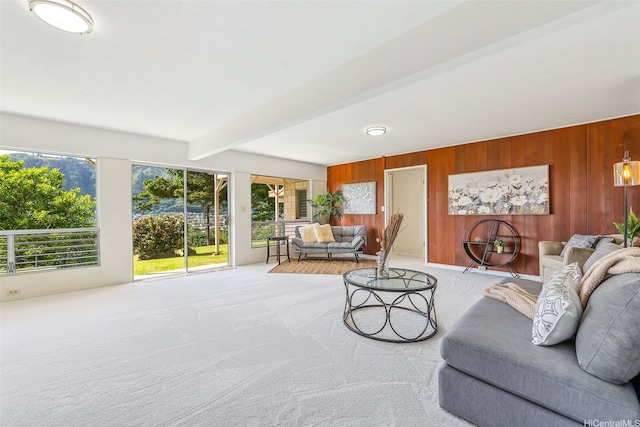 living room featuring beam ceiling, wooden walls, and light carpet
