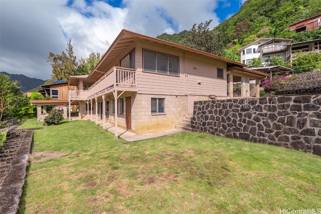 rear view of property with a yard, a balcony, and fence