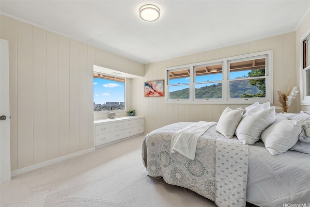 bedroom featuring baseboards, wood walls, and light carpet