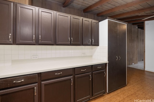 kitchen featuring dark brown cabinets, decorative backsplash, beamed ceiling, and light countertops