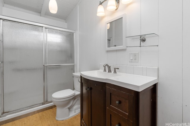 bathroom featuring a stall shower, toilet, vanity, and wood finished floors