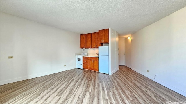 kitchen featuring white appliances, light countertops, light wood-style flooring, and baseboards