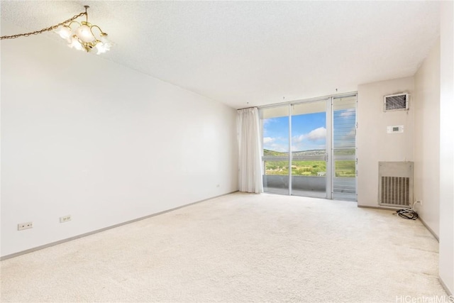 carpeted spare room featuring a chandelier, visible vents, baseboards, and expansive windows