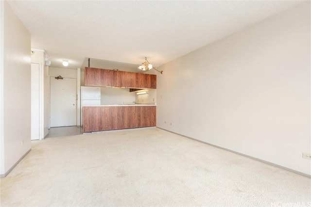 spare room featuring a notable chandelier, baseboards, and light carpet