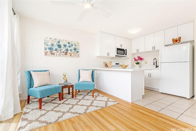 kitchen with light wood finished floors, light countertops, freestanding refrigerator, white cabinetry, and a ceiling fan