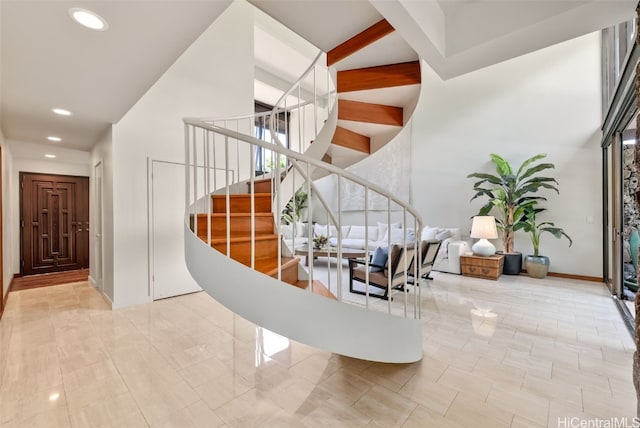 entryway with baseboards, stairway, a high ceiling, beam ceiling, and recessed lighting