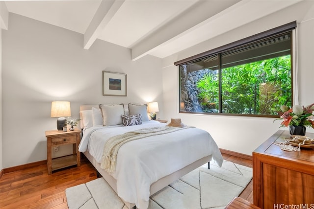 bedroom featuring baseboards, beamed ceiling, and hardwood / wood-style floors