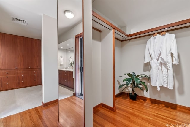 spacious closet with light wood-style flooring, visible vents, and a sink