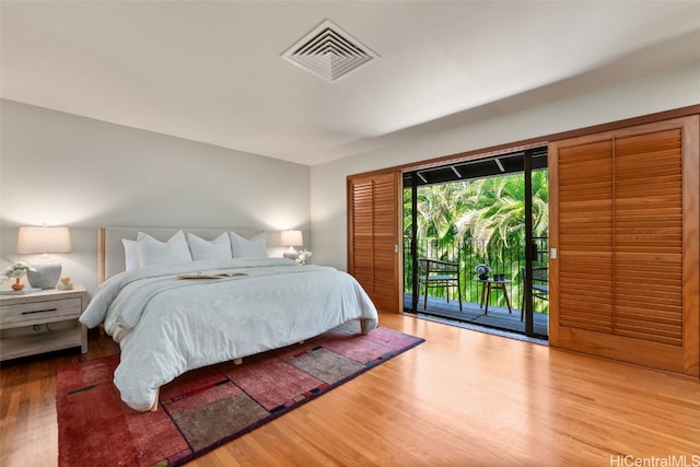 bedroom with access to exterior, visible vents, and wood finished floors