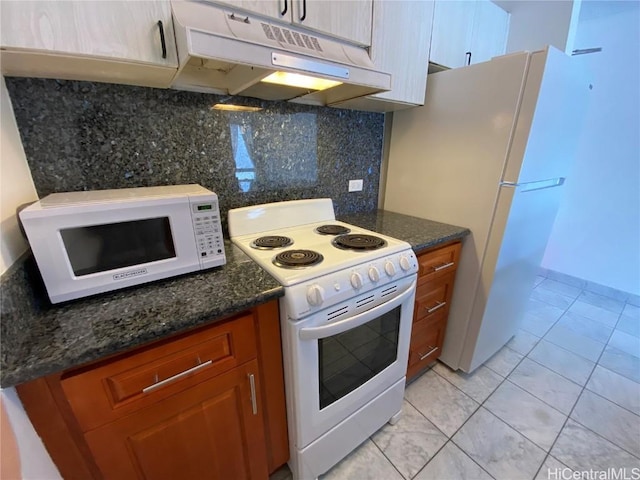 kitchen featuring brown cabinetry, white appliances, under cabinet range hood, and decorative backsplash