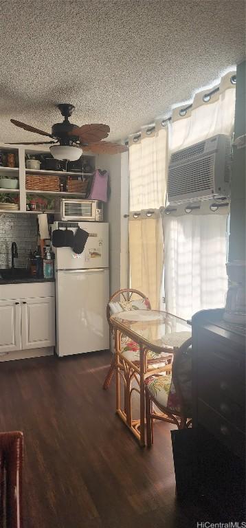 kitchen with a ceiling fan, freestanding refrigerator, dark wood finished floors, and a textured ceiling