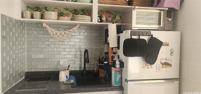 kitchen featuring freestanding refrigerator, a sink, dark countertops, and open shelves