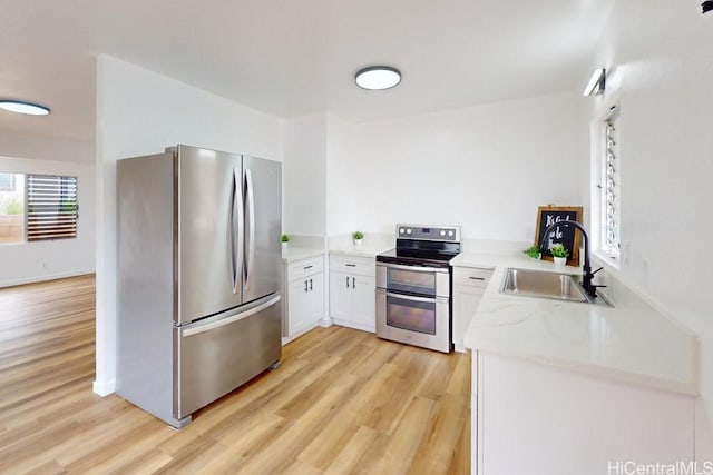 84-562 Nukea St, Waianae, HI 96792 - kitchen with appliances with stainless steel finishes, light wood-style floors, white cabinets, and light stone countertops