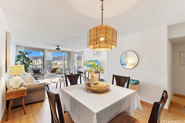 dining area featuring light wood-type flooring, a textured ceiling, ceiling fan, and floor to ceiling windows