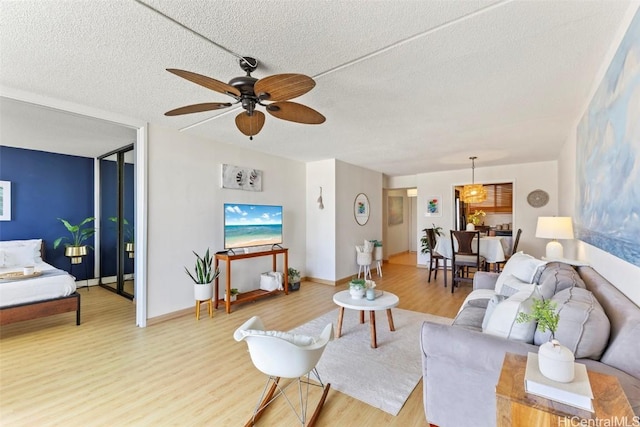 living area featuring a ceiling fan, wood finished floors, baseboards, and a textured ceiling