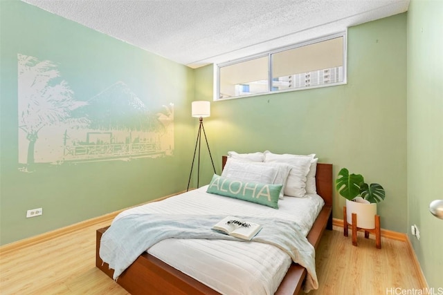 bedroom featuring wood finished floors, baseboards, and a textured ceiling