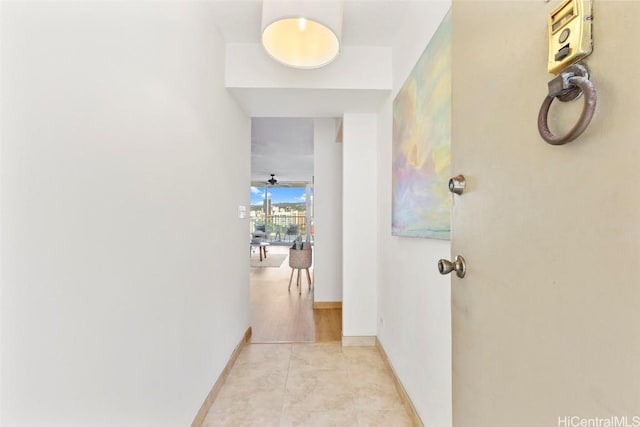 hall featuring light tile patterned floors and baseboards