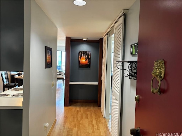 corridor featuring light wood-style floors and baseboards