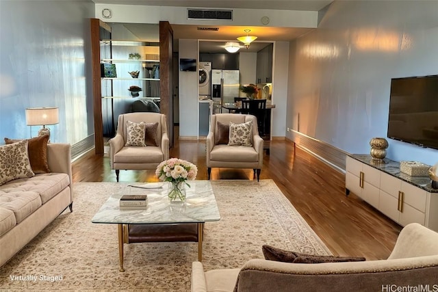 living area with visible vents, stacked washer / dryer, and wood finished floors