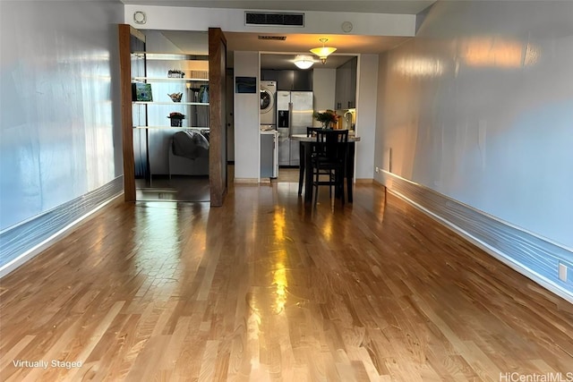 interior space featuring stacked washer / dryer, visible vents, baseboards, and wood finished floors