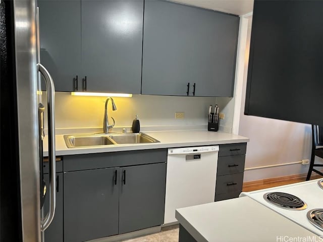 kitchen with freestanding refrigerator, gray cabinetry, white dishwasher, and a sink