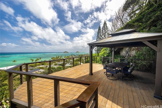 wooden deck with a gazebo, outdoor dining area, and a water view