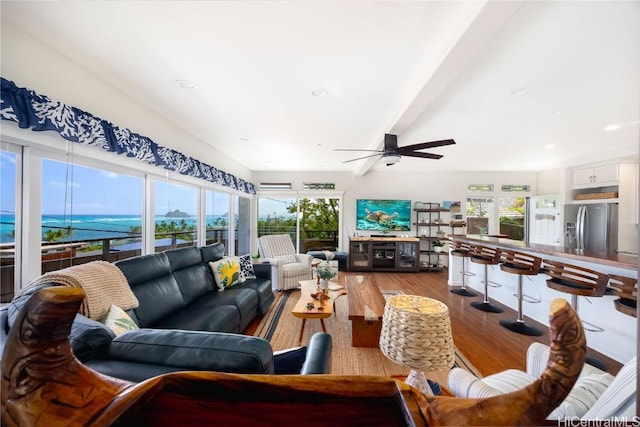 living room with ceiling fan, beamed ceiling, and wood finished floors