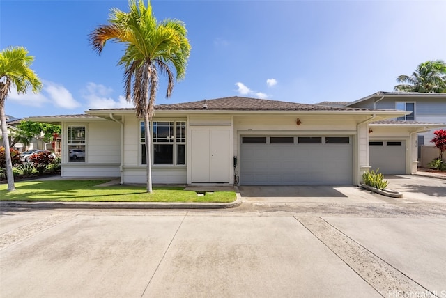 view of front of house with concrete driveway, an attached garage, and a front lawn