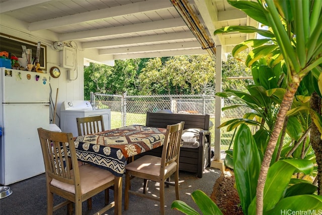 view of patio / terrace featuring washer / clothes dryer, outdoor dining area, and fence