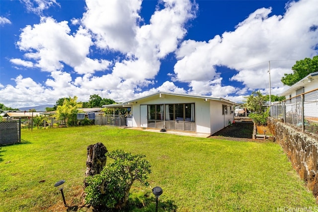 back of property featuring a lawn and fence