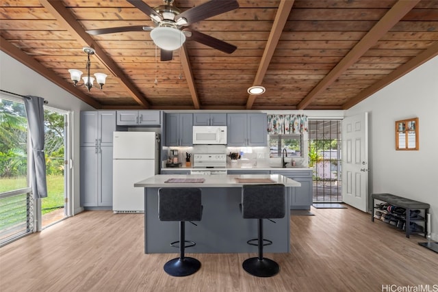 kitchen with light countertops, light wood-style flooring, lofted ceiling with beams, a sink, and white appliances