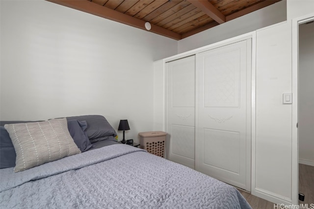 bedroom featuring a closet, wood ceiling, beamed ceiling, and wood finished floors