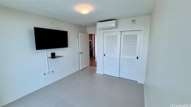 unfurnished bedroom featuring a closet, baseboards, and an AC wall unit