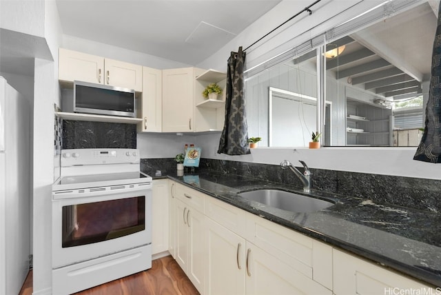 kitchen featuring open shelves, white electric range oven, stainless steel microwave, a sink, and dark stone countertops