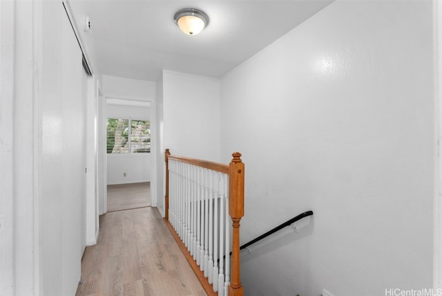 hall with light wood finished floors and an upstairs landing