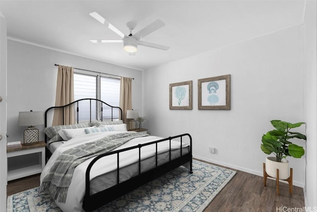 bedroom with a skylight, a ceiling fan, baseboards, and wood finished floors